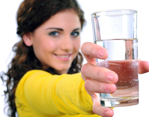 A homeowner shows off a glass of pure, clean water after using a Houston water softener.