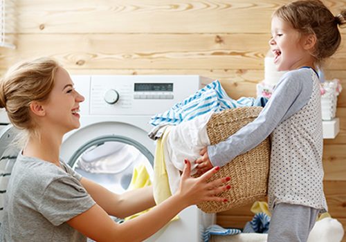 A mom and daughter remove clean, soft laundry from the dryer with the caption that reads, Clean Water for Your Entire Home.