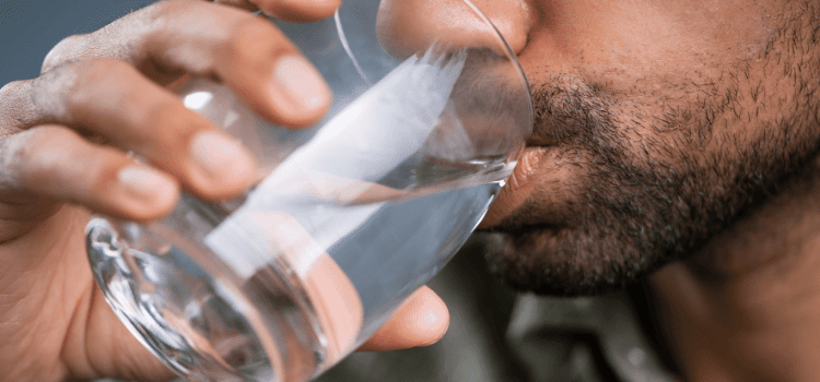 A Houston man drinks a glass of clean water filtered by Houston Water Solutions.