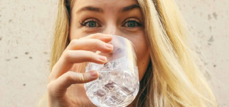 Girl experiencing the digestive benefits of water, happily sipping from a glass enhanced by water softeners in Houston TX.