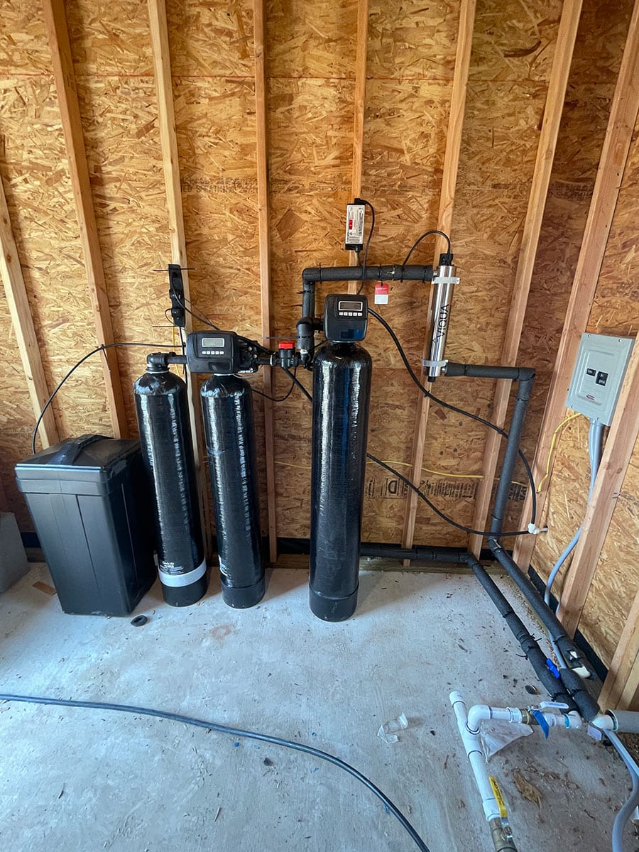 A full view of a twin tank water filtration system with an iron braker and UV lights.