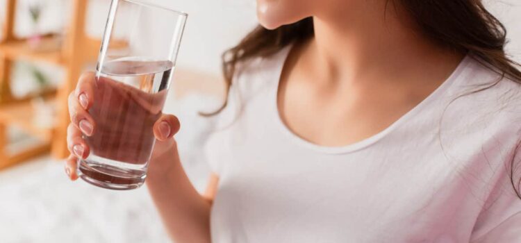 Woman enjoying a glass of water after installing a Houston water softener