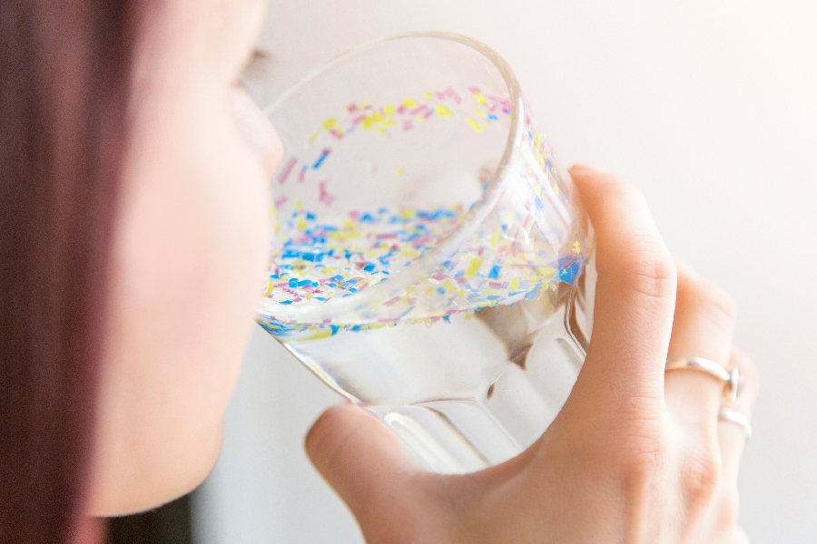 An individual preparing to drink water displaying visible microparticles resembling bacteria found in untreated Houston tap water prior to Houston water filtration and softener installation.