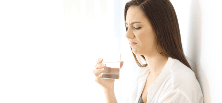 Displeased woman tasting unpleasant water, isolated on white background - Considering Houston TX water filtration solutions.