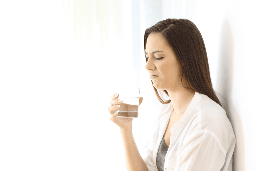 Displeased woman tasting unpleasant water, isolated on white background - Considering Houston TX water filtration solutions.