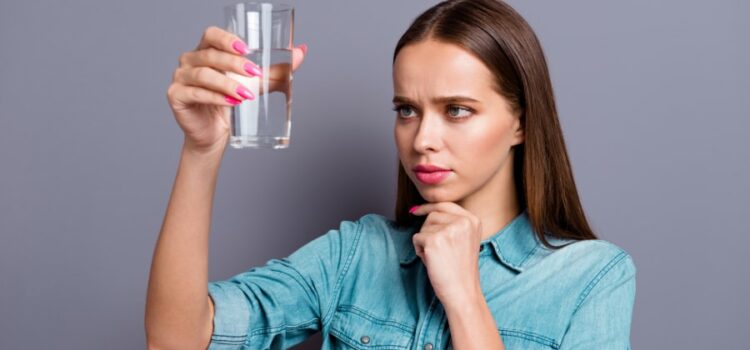 Woman looking at water that was filtered through a water softener service in Houston