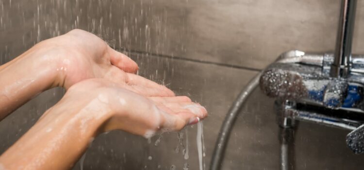 Hands catching water from the Houston Water Purification System connected to the shower