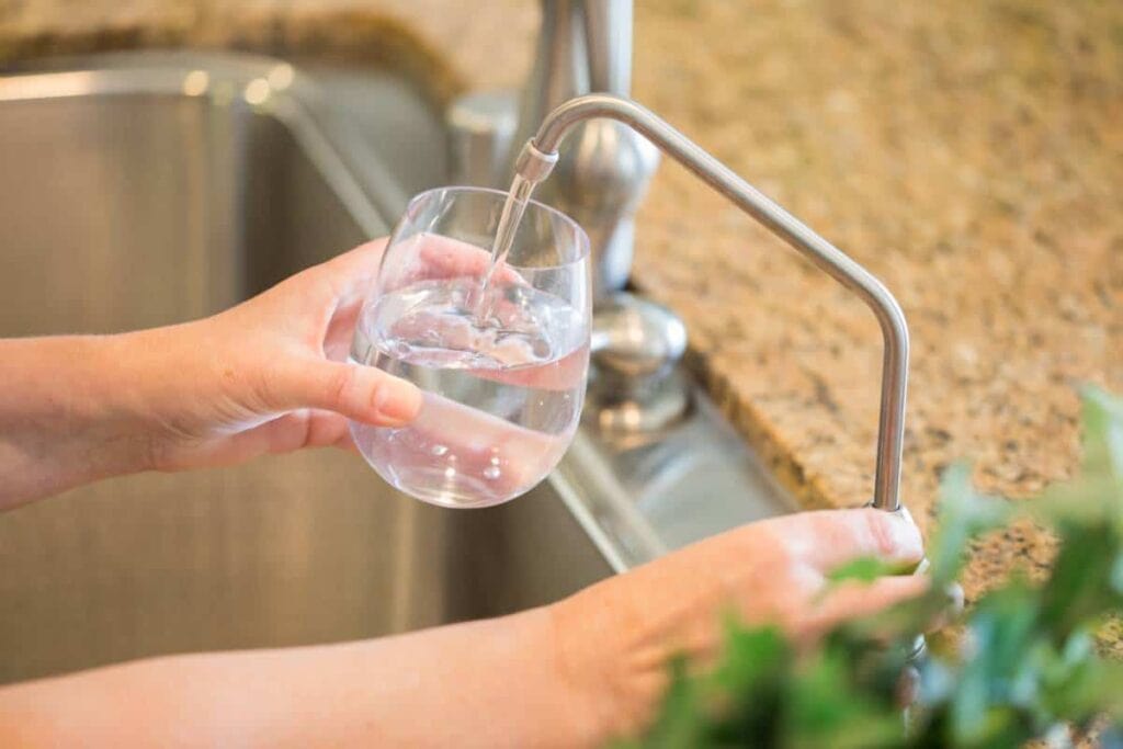 An image of a person drinking clear water through her reliable Houston water conditioners