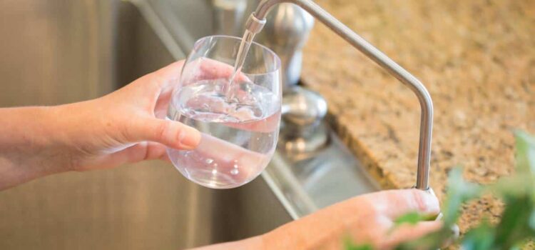 An image of a person drinking clear water through her reliable Houston water conditioners