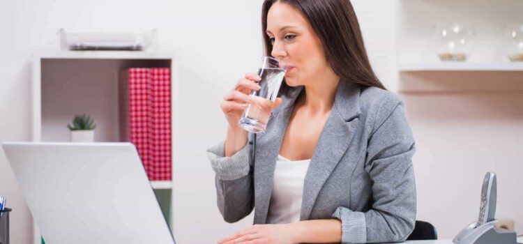 woman drinking a glass of clean water from the filter at work