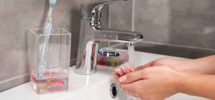 A person filling a glass with clean water from a tap, showcasing Houston water treatment.