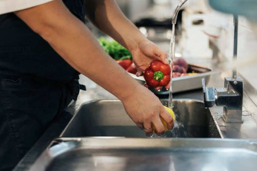A chef in a restaurant washing vegetables with water improved by water filtration in The Woodlands.