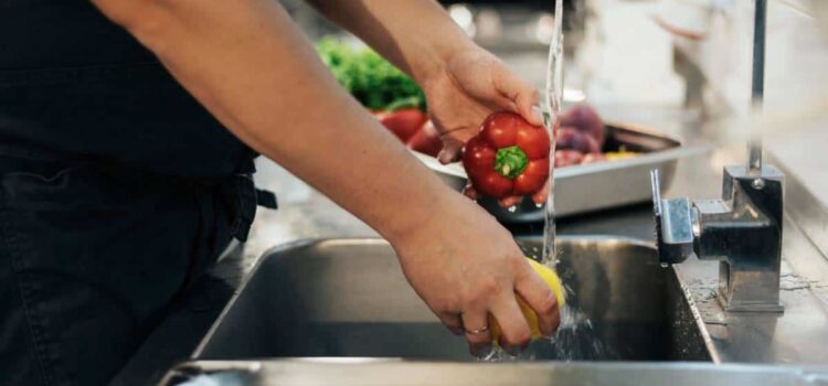 A chef in a restaurant washing vegetables with water improved by water filtration in The Woodlands.