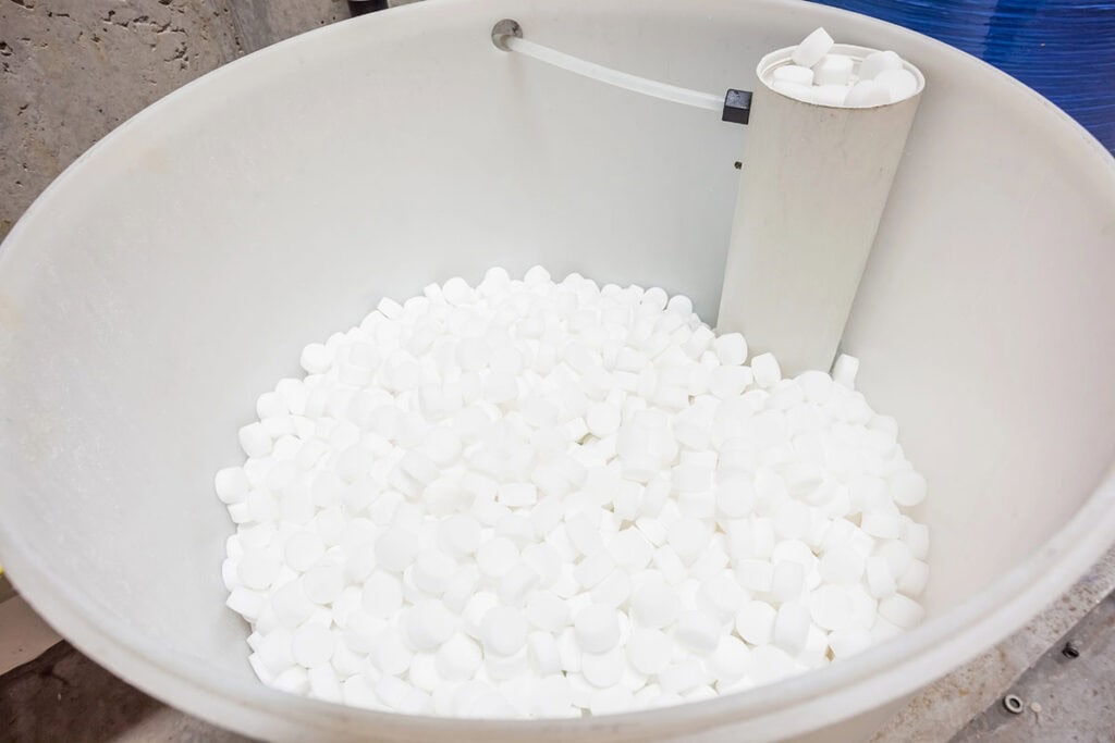 A water softener's salt container is shown, filled with salt.