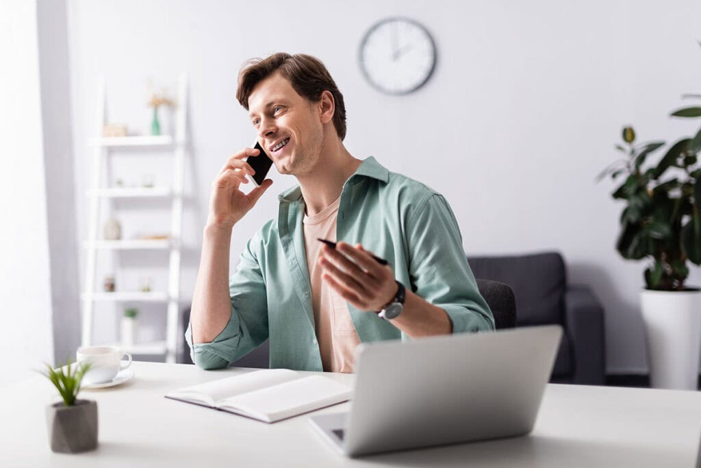 A man is talking on a phone, with a notepad ready to take notes.