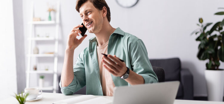 A man is talking on a phone, with a notepad ready to take notes.