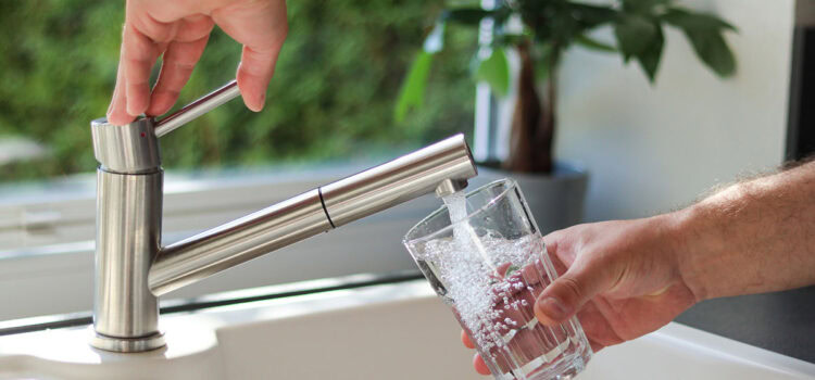 A man is pouring tap water into a glass.